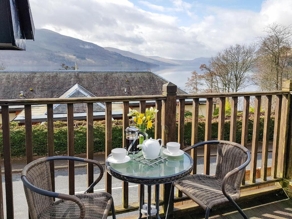 a table and chairs on a balcony with a view at The Old Post Office On Loch Tay in Stron-fearnan