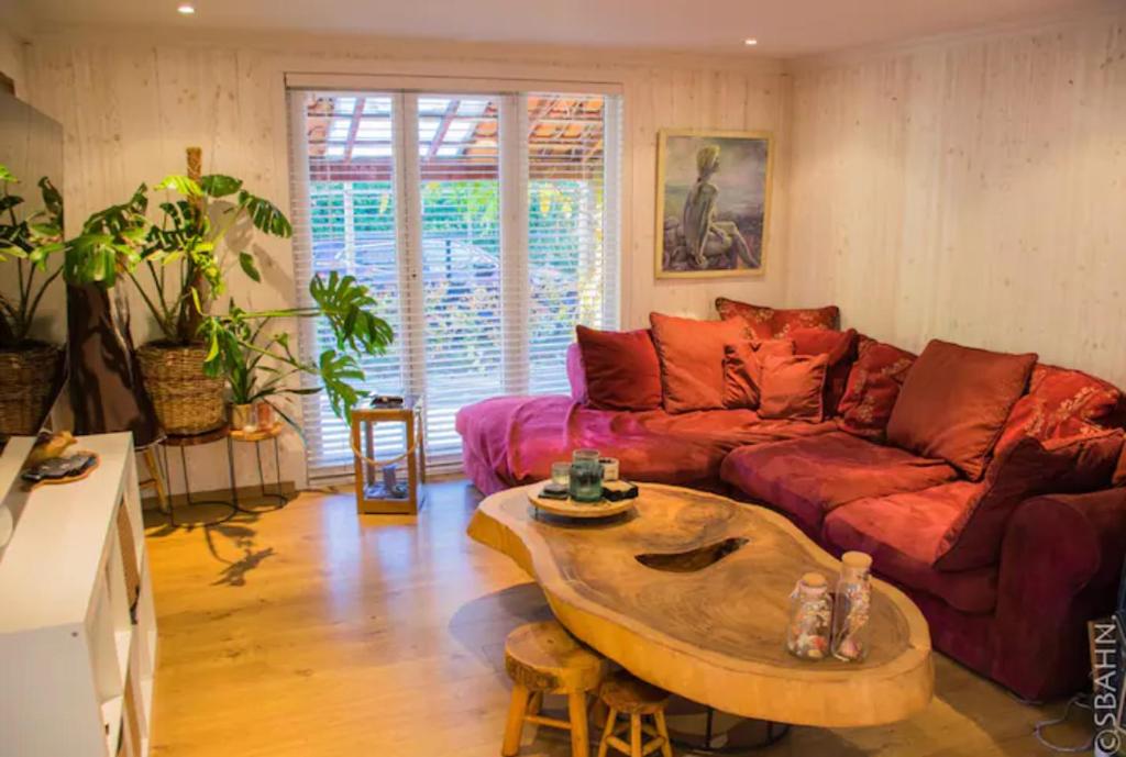 ein Wohnzimmer mit einem roten Sofa und einem Couchtisch in der Unterkunft Le Petit Chalet avec hottub. in Sint-Gillis-Waas