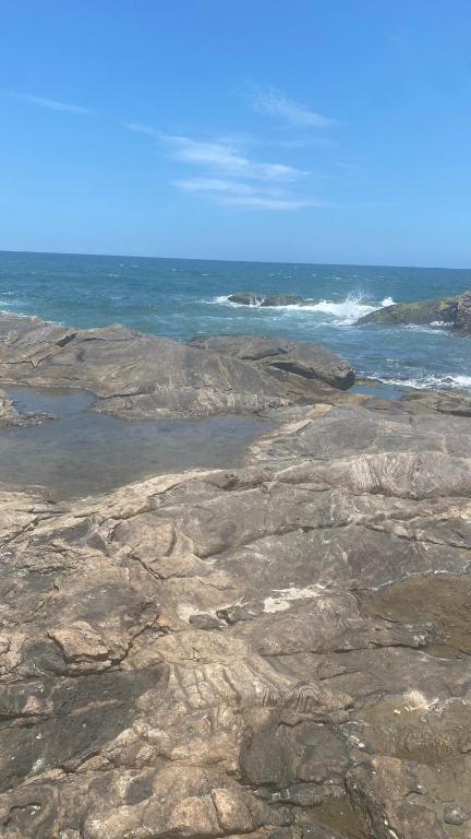 a rocky shoreline with the ocean in the background at Casa das Gaivotas in Itanhaém