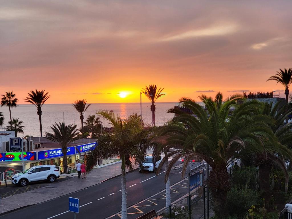 a sunset over a street with palm trees and the ocean at Beach Apartment Bungamericas - Sea View Playa de las Americas in Playa de las Americas