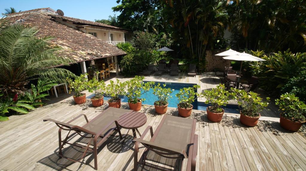 um pátio com mesas, cadeiras e plantas e uma piscina em Ilha Deck Hotel em Ilhabela