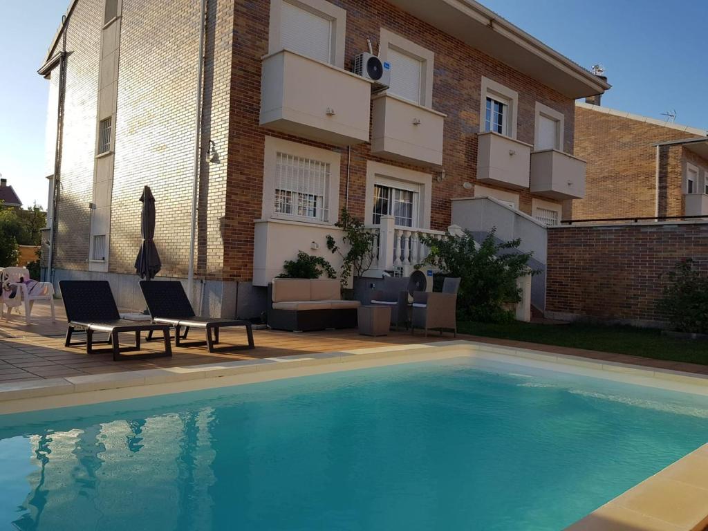 a swimming pool with two chairs and a building at Chalet Villa Maria a 10 minutos de Puy du Fou in Burguillos de Toledo