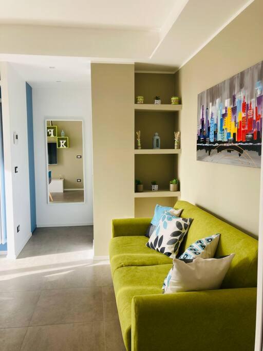 Hotel FK HOUSE - Casa moderna con vista Olimpiadi 2026, a living room with a green couch with pillows at FK HOUSE - Casa moderna con vista Olimpiadi 2026 in Milan