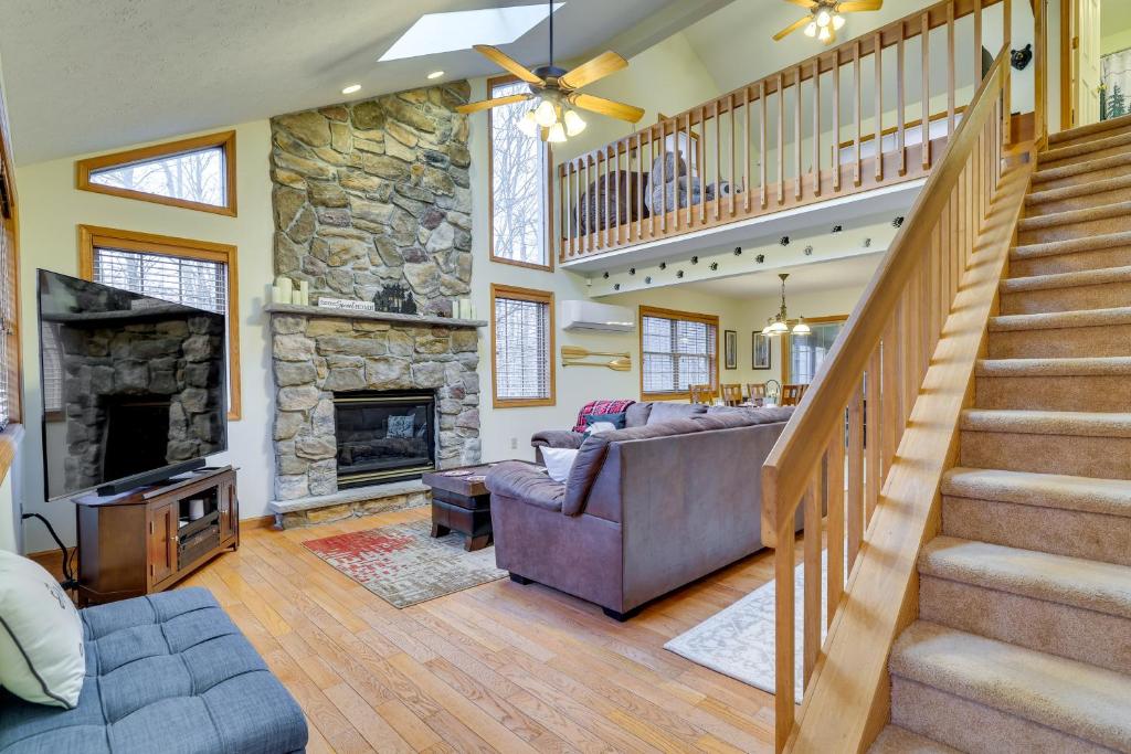 a living room with a staircase and a stone fireplace at Cozy Big Bass Lake Home with Hot Tub and Game Room! in Gouldsboro