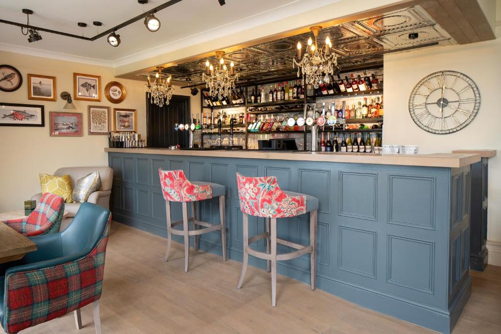 a blue bar with stools in a restaurant at The Manor Coastal Hotel & Inn, Blakeney - part of The Coaching Inn Group in Blakeney