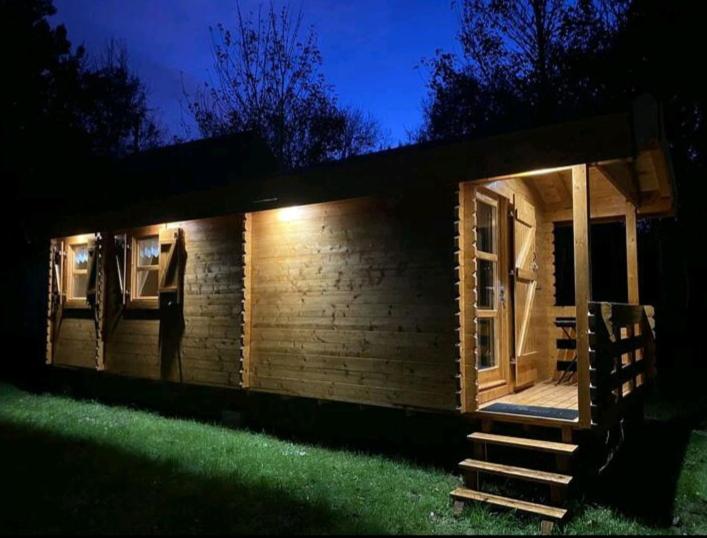 une petite cabane en bois avec une terrasse couverte la nuit dans l'établissement Roulotte la Bohême est son Spa en Baie de Somme, à Arrest