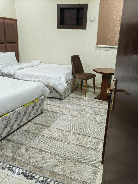 a room with two beds and a chair and a table at شقق أجياد السد in Mecca