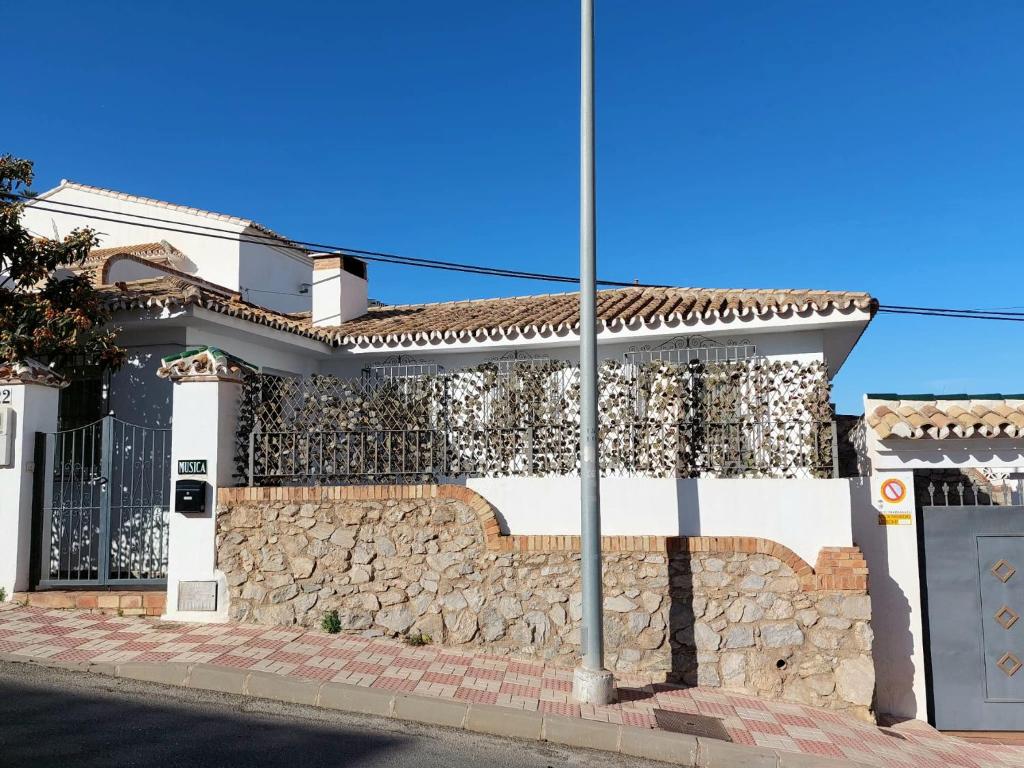 ein weißes Haus mit einer Steinmauer in der Unterkunft Villa Musica in Torremolinos