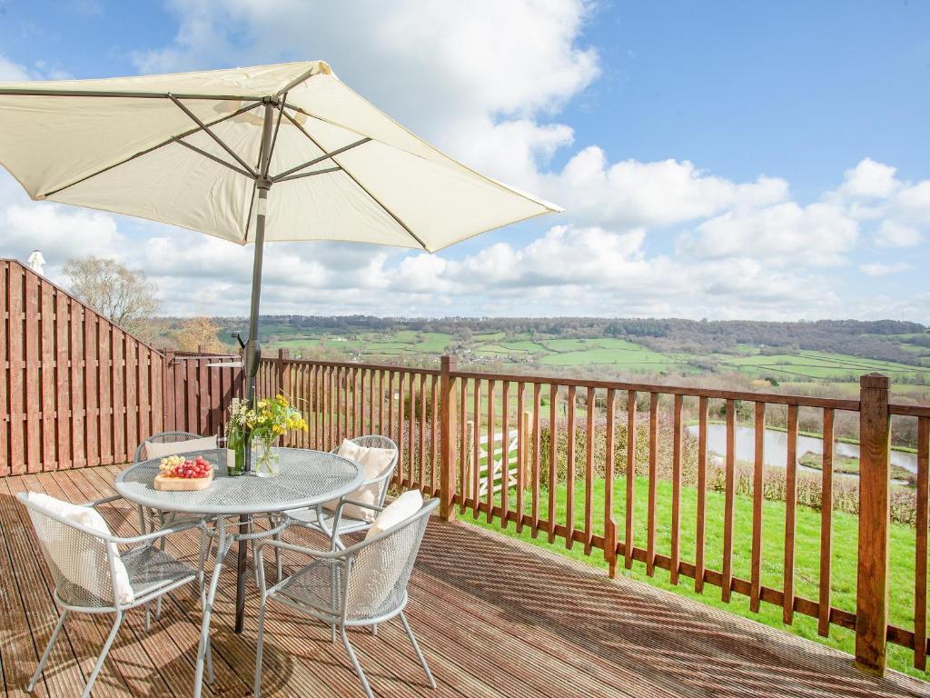 a table and chairs on a deck with an umbrella at Stargazer - Uk43267 in Luppitt