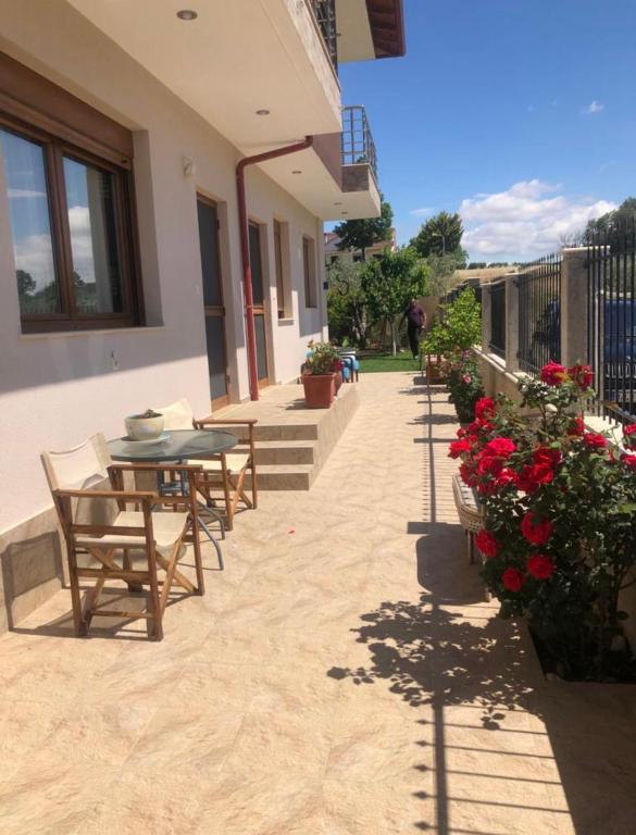a patio with a table and chairs and flowers at Guesthouse Dimitra in Paralia Dionysiou