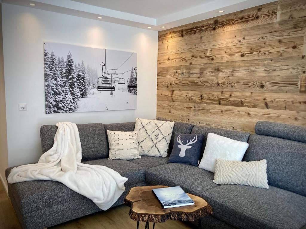 a living room with a gray couch and a wooden wall at Spacious 3 Room Apartment - Family-Friendly - Central Leukerbad - Great Views in Leukerbad