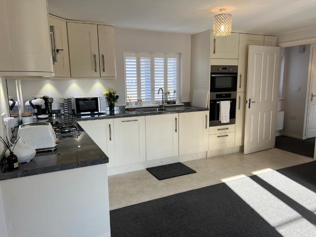 a kitchen with white cabinets and a black counter top at Cathedral Coach House in Lichfield