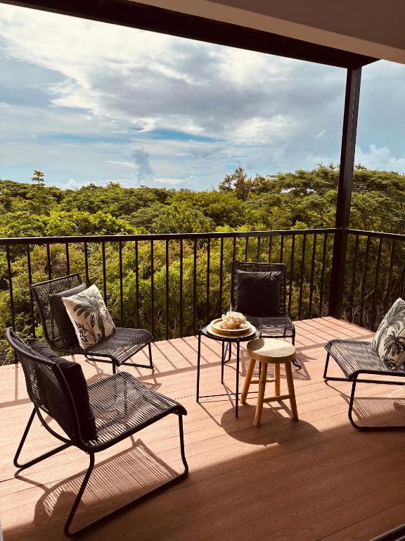 a patio with three chairs and a table on a deck at Appartement NOAM, Mont Choisy in Mont Choisy
