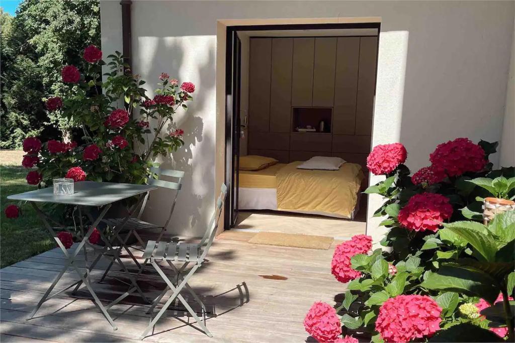 ein Schlafzimmer mit einem Bett, einem Tisch und Blumen in der Unterkunft Chambre indépendante avec sdb et toilettes privées dans une maison en forêt proche du golf et de la plage Entree indépendante avec acces privé in Le Touquet-Paris-Plage