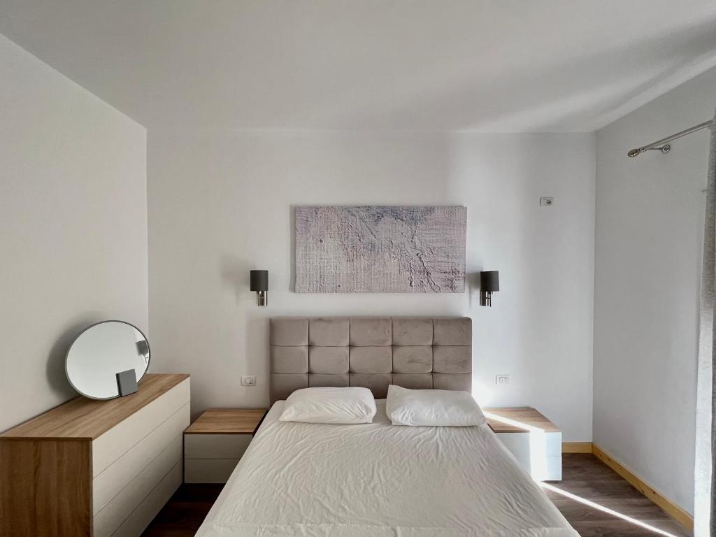 Habitación blanca con cama y espejo en Argileos Rooms, en Himare
