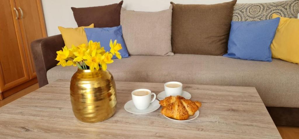 un tavolo con un vaso d'oro e due tazze e croissant di Apartament rustykalny a Jelenia Góra