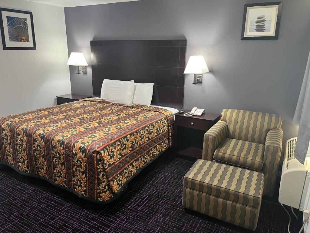 um quarto de hotel com uma cama e uma cadeira em Broadway Inn Motel em San Antonio