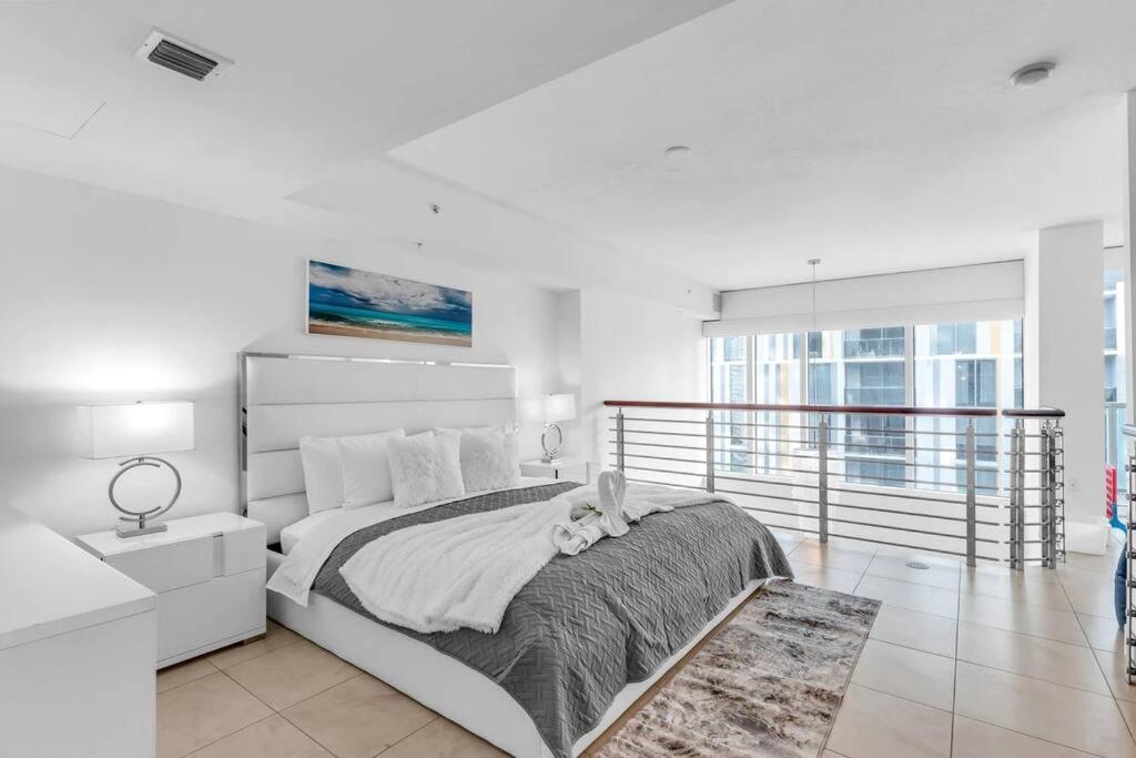 a white bedroom with a large bed and a balcony at Sublime Views 2BR double balcony loft in Miami