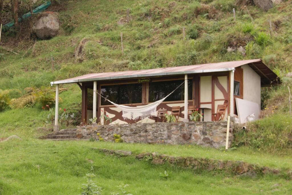 una casa en una colina con una hamaca delante en Cabaña Villa Esperanza, en Santandercito