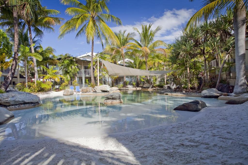 a swimming pool on a beach with palm trees at Marlin Cove Holiday Resort in Trinity Beach
