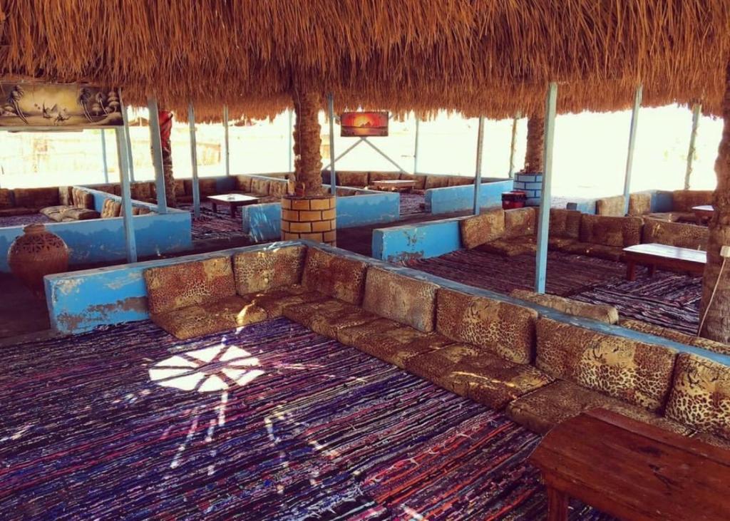 a room with a couch and a straw roof at Free Beach Camp in Nuweiba‘ el Muzeinah