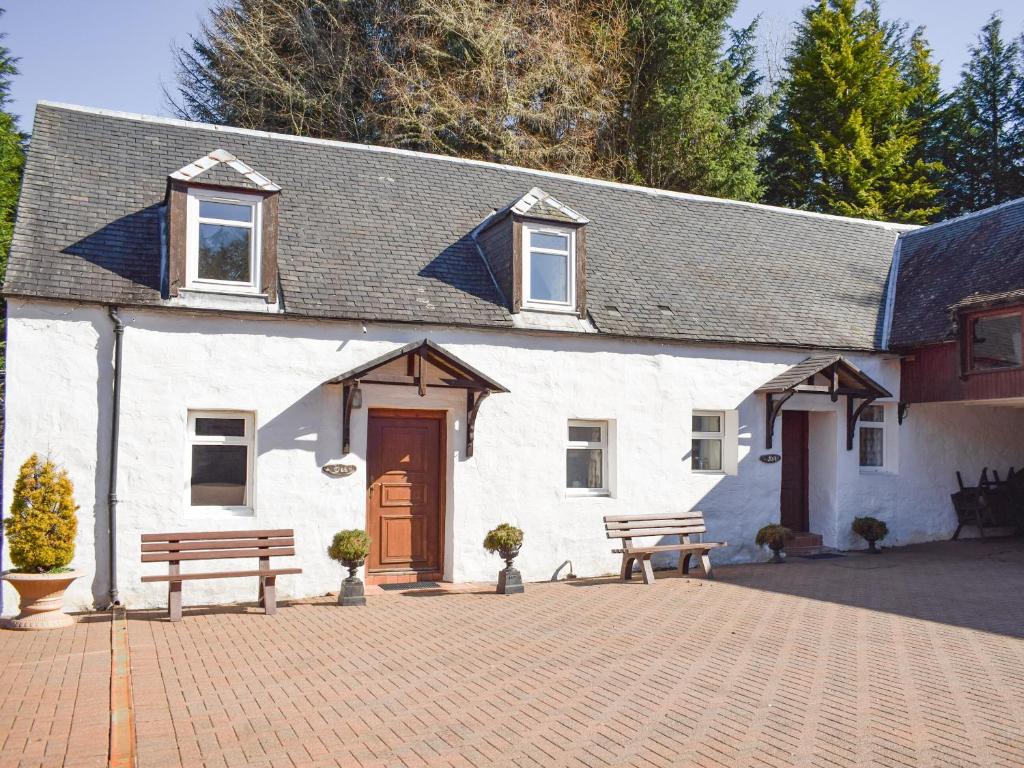 a white building with two benches in front of it at Oak Cottage - Uk43458 in Killin