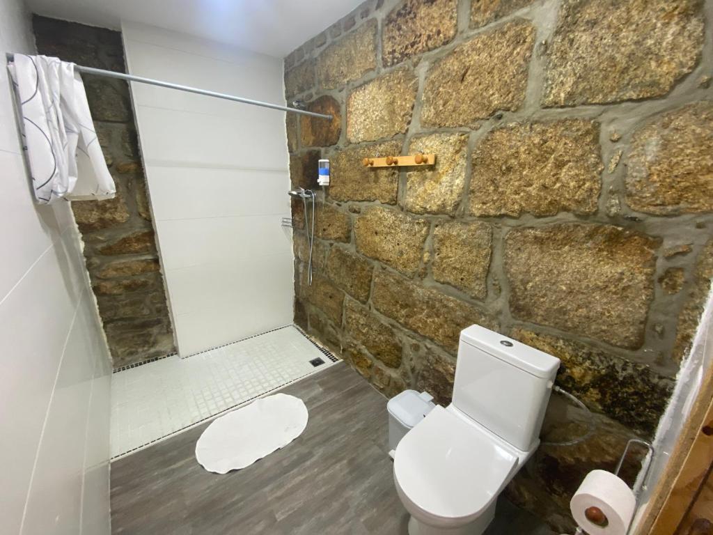 a bathroom with a white toilet and a stone wall at Casa do Avô Grande in Esposende