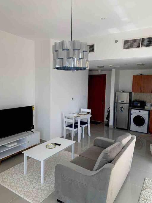 a living room with a couch and a table and a tv at One Bedroom Apartment- IMPZ in Dubai