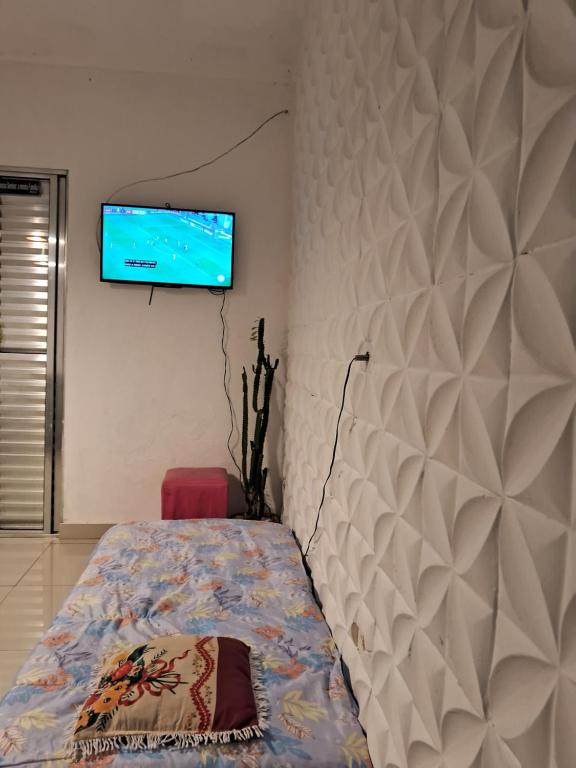 1 dormitorio con 1 cama y TV de pantalla plana en la pared en Minha casa sua casa completa, en Guarulhos