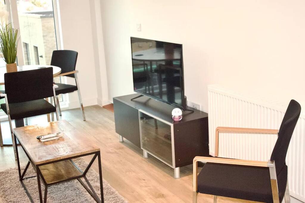 a living room with a flat screen tv and chairs at Apartment in the heart of london Greenford in Perivale
