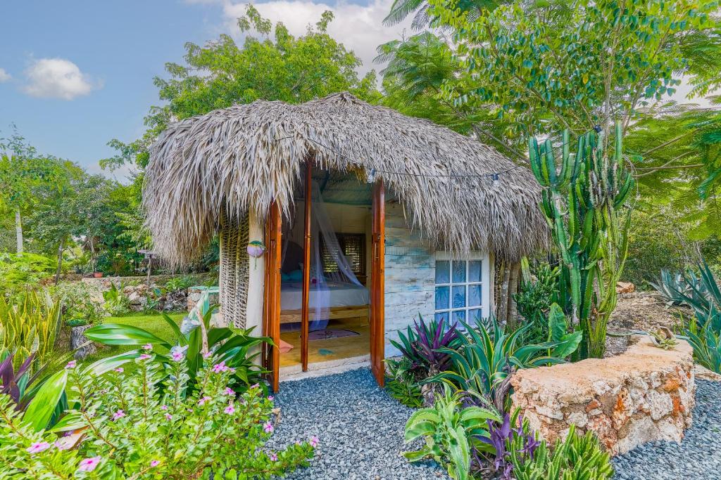 eine kleine Hütte mit Strohdach in einem Garten in der Unterkunft GuaiGüí Bayahibe in Bayahibe