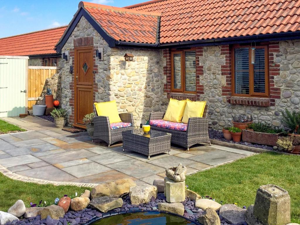 Stolford的住宿－Mudhorse Cottage，一个带2把藤椅和池塘的庭院