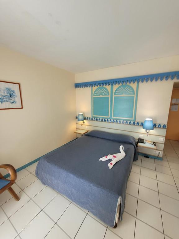 a bedroom with a large bed with a blue headboard at Hotel Carayou piscine et Spa in Les Trois-Îlets