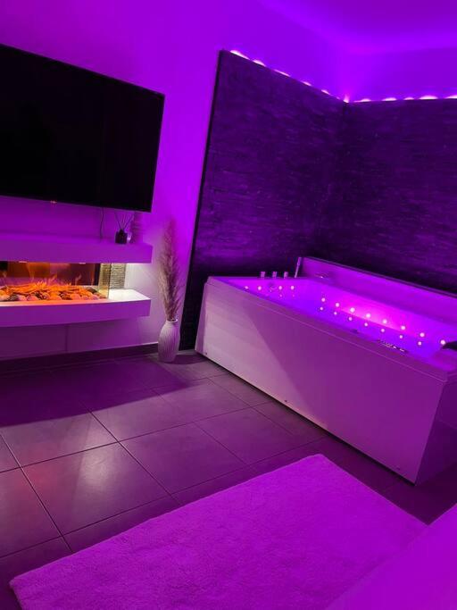 カステルノ・ル・レにあるLa suiteの紫色の客室で、バスタブ、テレビが備わります。