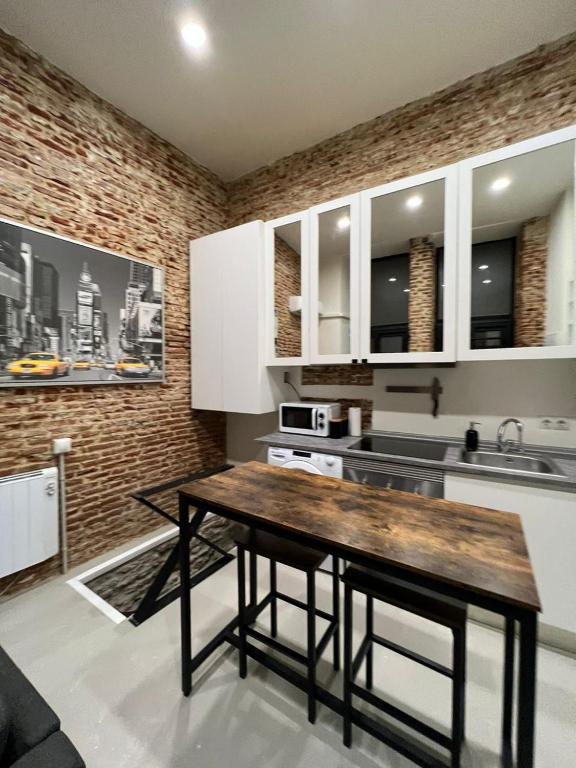 a kitchen with white cabinets and a wooden table at Moderno y luminoso departamento. in Madrid