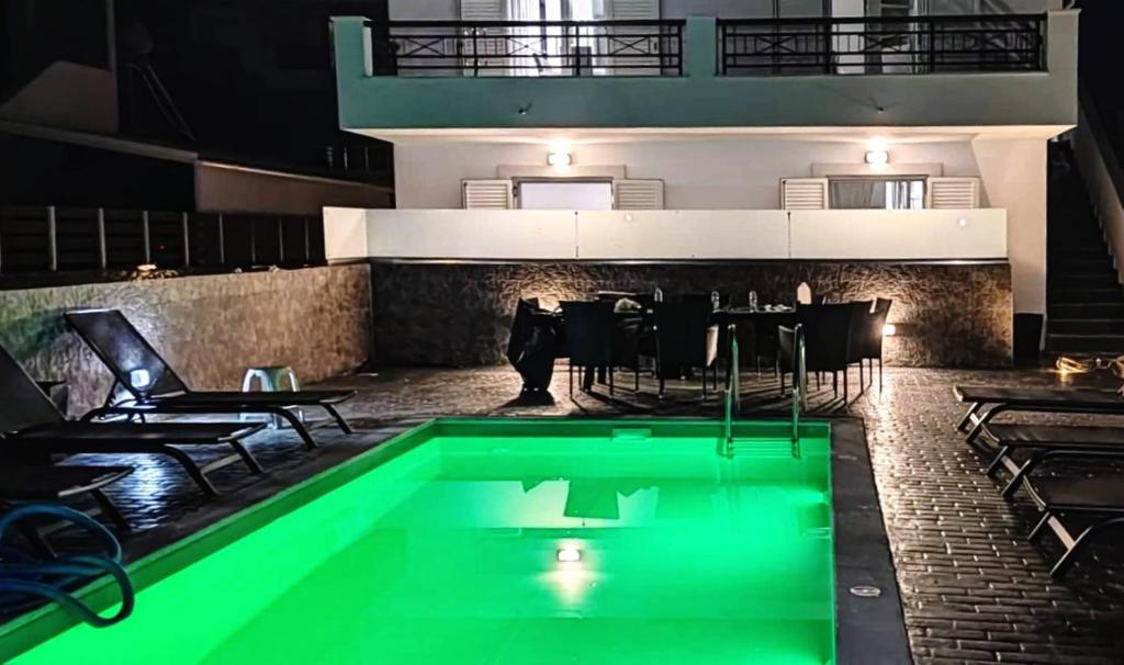 Villa Peskena's في Potamós: مسبح مع اضاءة خضراء بجانب مطعم