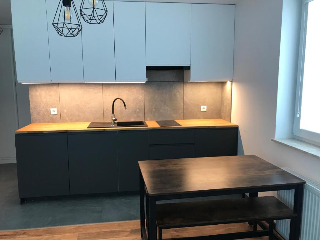 a kitchen with blue cabinets and a table and a sink at Pszczelna Loft in Kraków