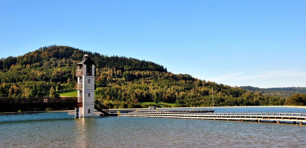 a lighthouse in the middle of a lake with a bridge at Pokoje Gościnne Nad Zalewem w Starej Morawie in Stronie Śląskie