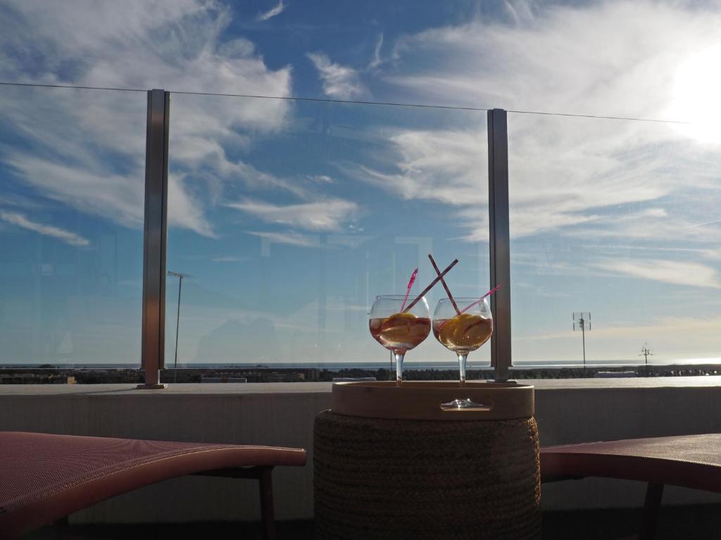 Charming V2 next to ocean, golf & natural reserve في ألبوفيرا: كأسين من النبيذ يجلسون على طاولة أمام النافذة