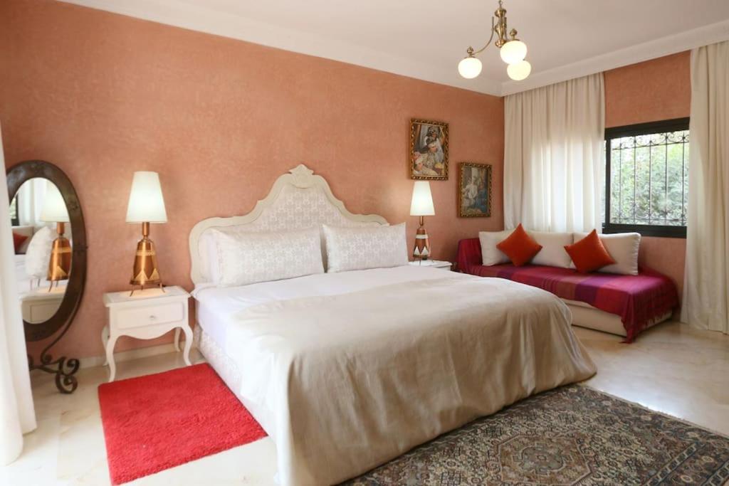 een slaapkamer met een groot wit bed en een rode bank bij Exceptionnel Villa 6 Rooms 12 guests Big Pool in Marrakesh