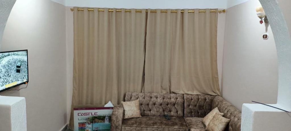a living room with a couch in front of a window at Dakrour flat in ‘Izbat Ţanāţī