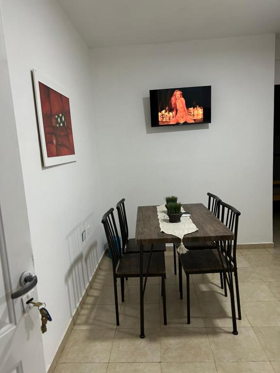 mesa de comedor con sillas y TV en la pared en Departamento Capital en La Rioja