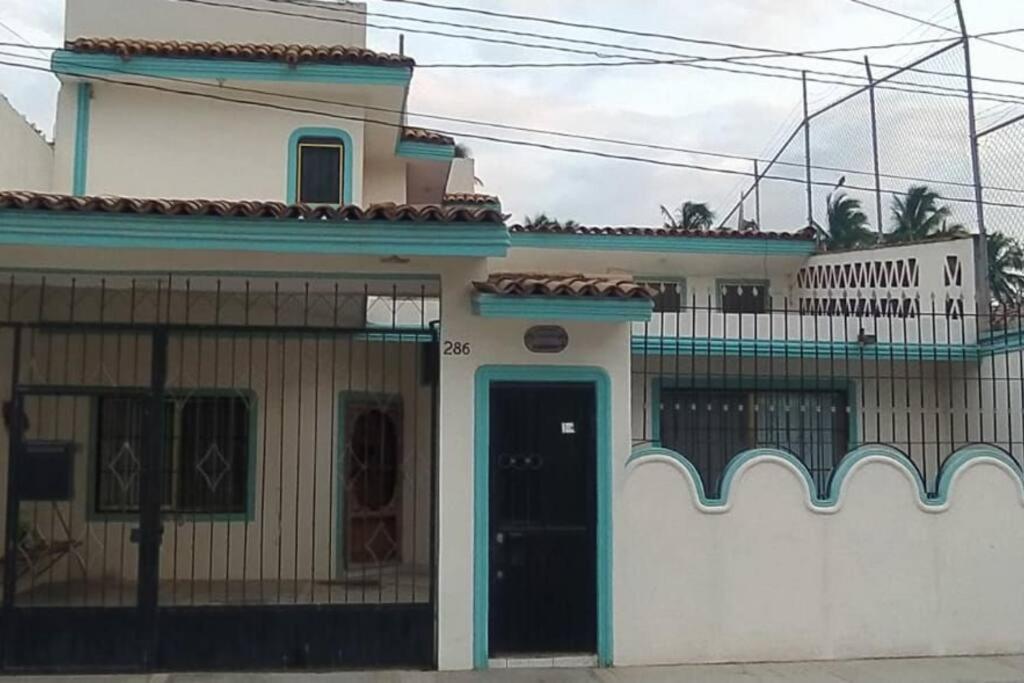 a white house with a blue door and a balcony at Casa Las Palmas Barra de Navidad, Jalisco. in Barra de Navidad