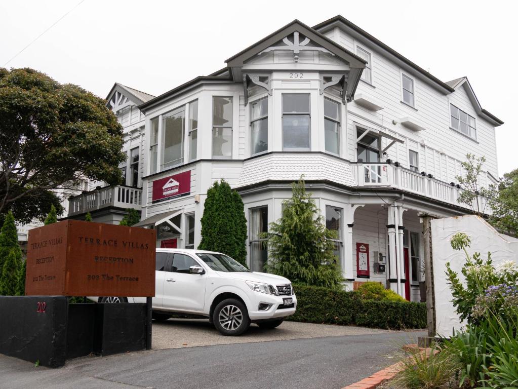 um carro branco estacionado em frente a uma casa branca em The Terrace Villas Serviced Apartments em Wellington