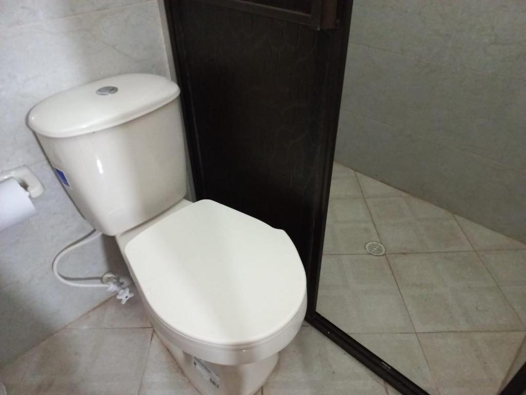 a white toilet in a bathroom with a roll of toilet paper at Apartamentos con estacionamiento cerca al parque in Támesis