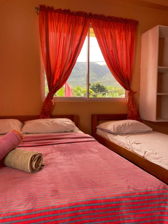 two beds in a room with a window at Medano Sunset Resort in Mambajao