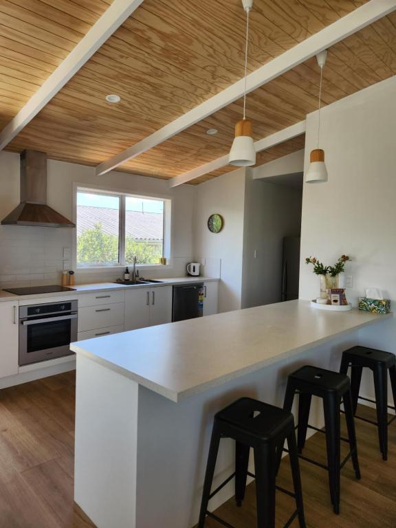 una cocina con una gran isla blanca con taburetes negros en Beautifully renovated townhouse, easy walk to CBD en Blenheim