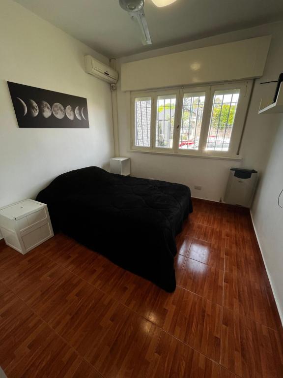 a bedroom with a black bed and wooden floors at Casa con patio! Hermosa zona y muy silenciosa! in Beccar