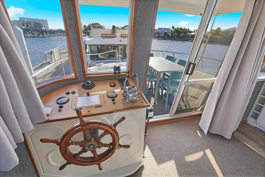 a boat with a steering wheel in a room with windows at Caloundra Houseboats in Pelican Waters