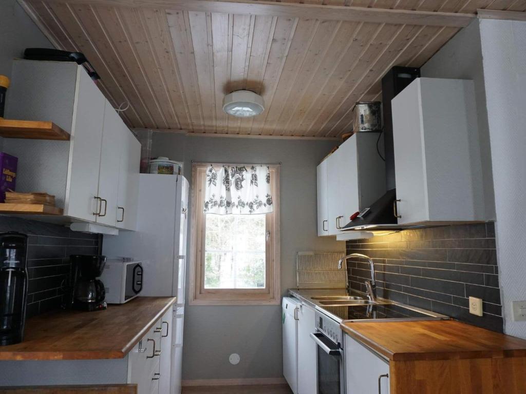 une cuisine avec des placards blancs et une fenêtre dans l'établissement Holiday home MUNKEDAL VI, à Munkedal